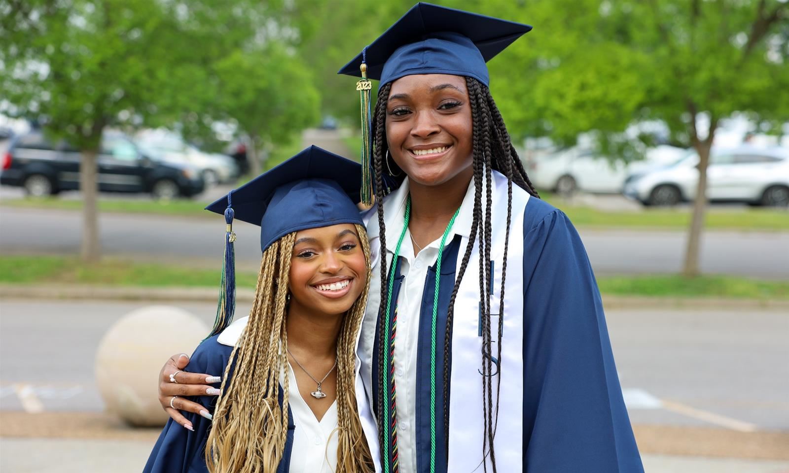 Two graduates smile